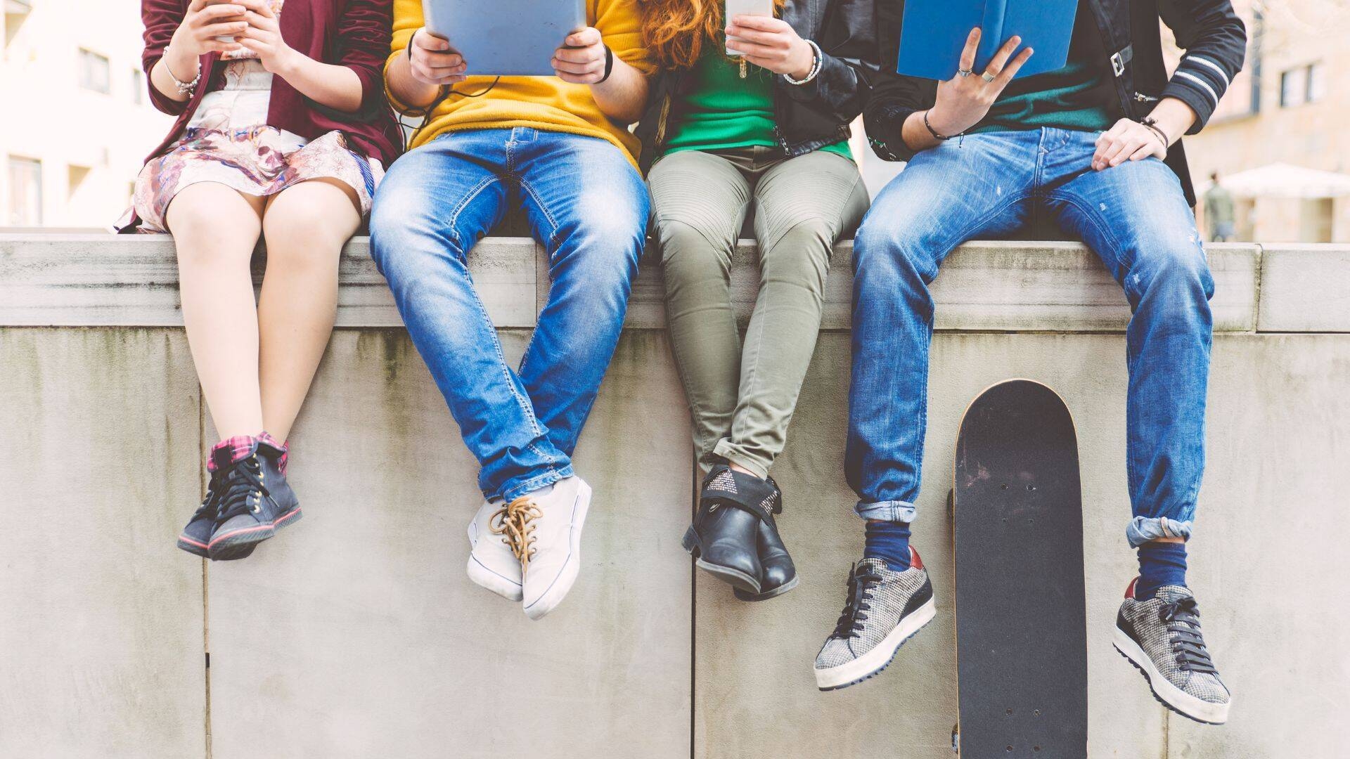 Foto gambe adolescenti seduti su un muretto