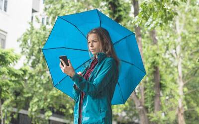 foto di una signora sotto all'ombrello che guarda il cellulare