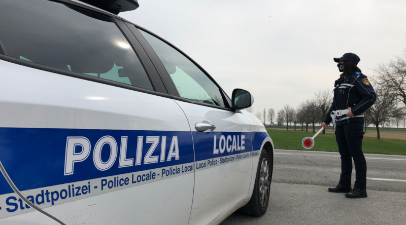 un agente di polizia locale mentre effettua un controllo accanto all'auto di servizio